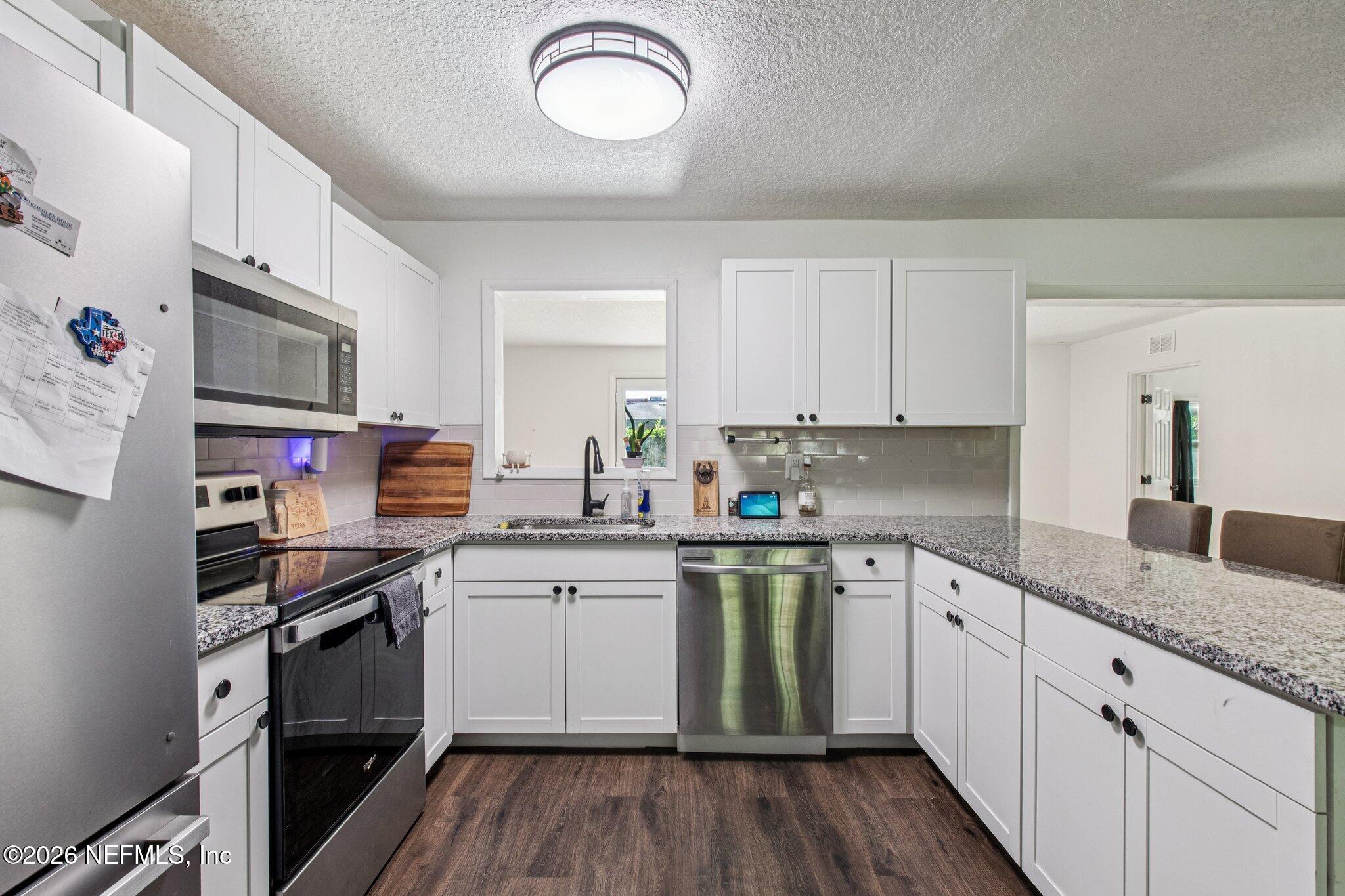 1417 Clock Street Jacksonville, FL 32211 - Photo 16 of 39 a kitchen with stainless steel appliances granite countertop a sink dishwasher stove and white cabinets with wooden floor