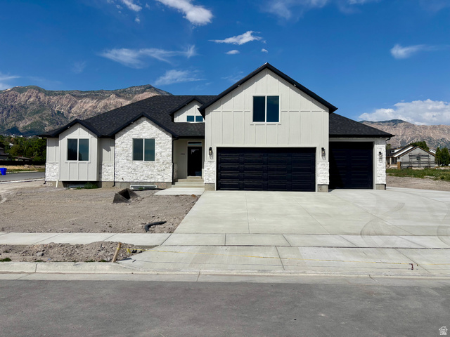 1184 West 3250 North Ogden, UT 84414 - Photo 1 of 69 Modern farmhouse exterior featuring vertical white siding, white stone accents, a dark shingle roof, two black garage doors, and a concrete driveway