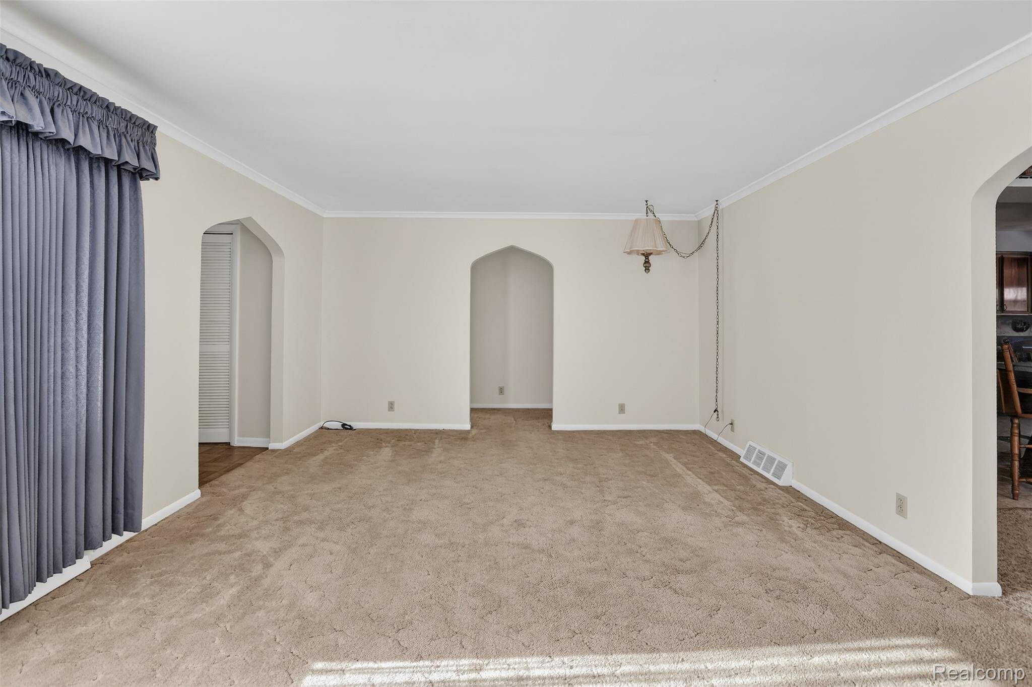 3241 Curtis Road Birch Run, MI 48415 - Photo 13 of 47 Spare room with arched walkways, light colored carpet, and crown molding