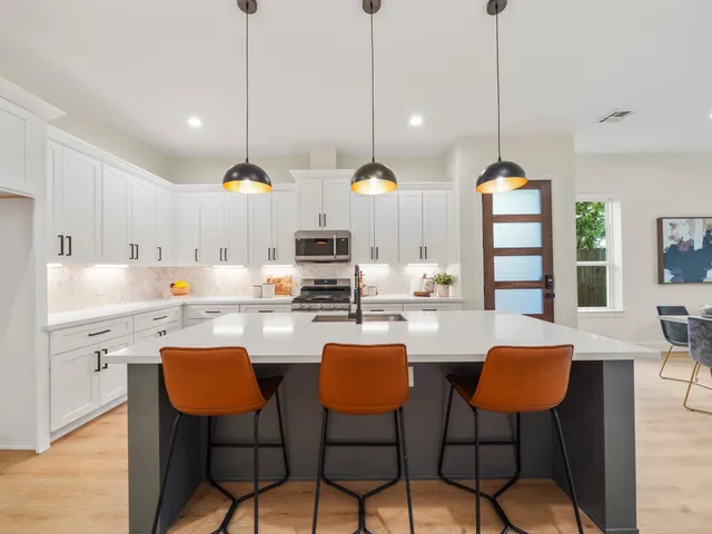 a kitchen with stainless steel appliances kitchen island a large white table chairs and white cabinets