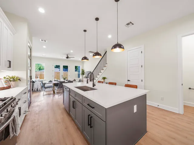 a view of a kitchen with a sink a stove and chairs