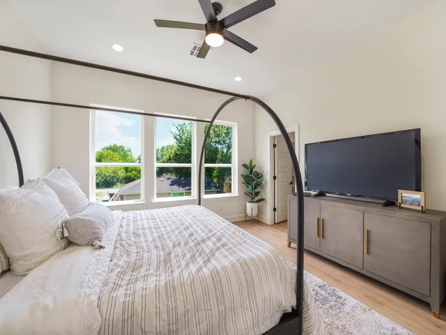 a bedroom with a bed flat screen tv and a large window