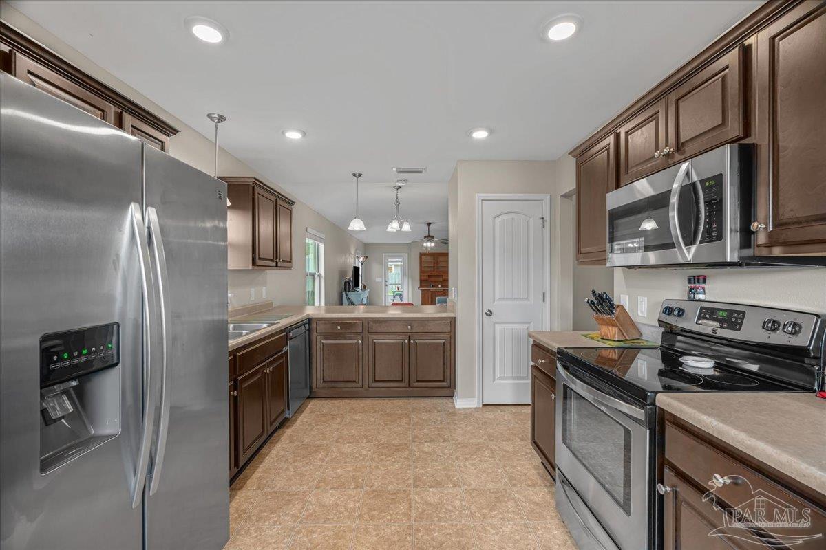 5797 Corkscrew Court Pace, FL 32571 - Photo 12 of 43 a kitchen with stainless steel appliances granite countertop a refrigerator stove and sink