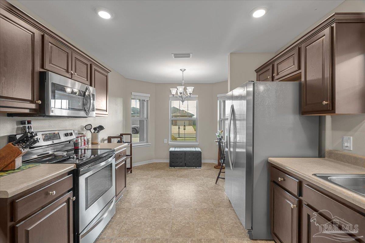 5797 Corkscrew Court Pace, FL 32571 - Photo 16 of 43 a kitchen with a sink stove and refrigerator
