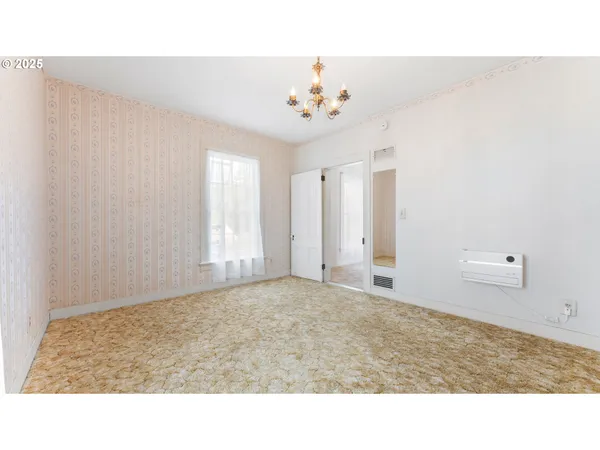 a room with a chandelier fan and a window
