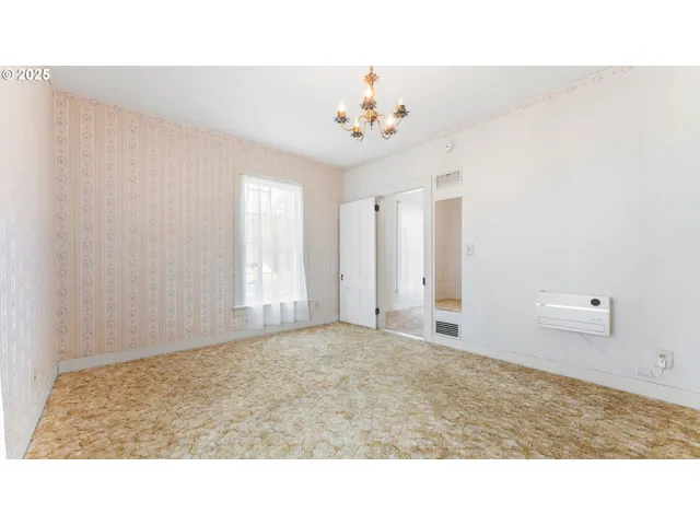 a room with a chandelier fan and a window