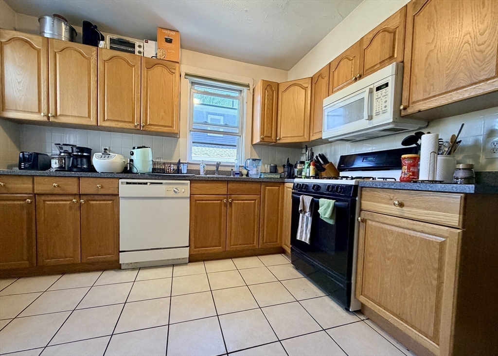 91 Academy Hill Road, Unit 91 Boston, MA 02135 - Photo 9 of 15 a kitchen with stainless steel appliances granite countertop a stove a sink dishwasher and cabinets with wooden floor
