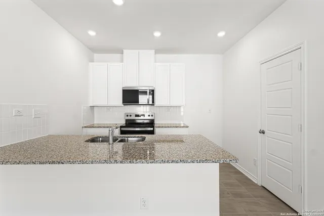 a kitchen with granite countertop white cabinets and stainless steel appliances