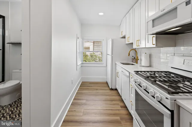 a kitchen with stainless steel appliances white cabinets a stove a sink and a window