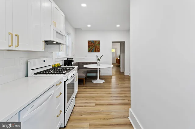 a kitchen with stainless steel appliances granite countertop a sink a stove and white cabinets with wooden floor
