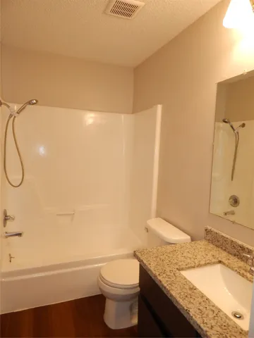 a bathroom with a granite countertop sink a toilet and shower