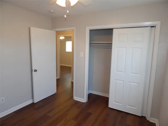 an empty room with wooden floor and closet area