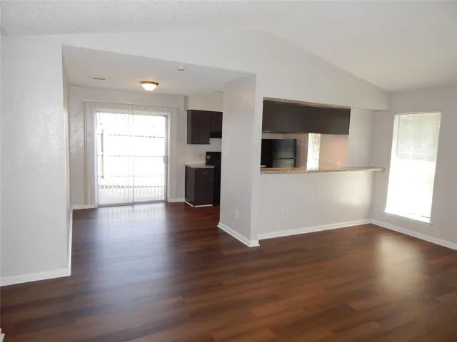 a view of a livingroom with wooden floor and a kitchen space