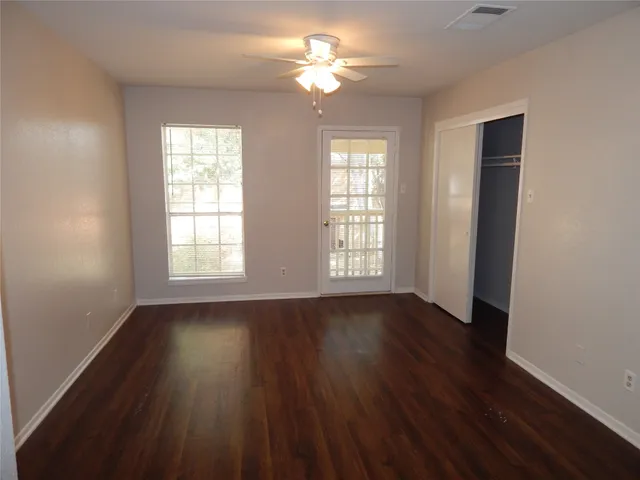 an empty room with wooden floor and windows