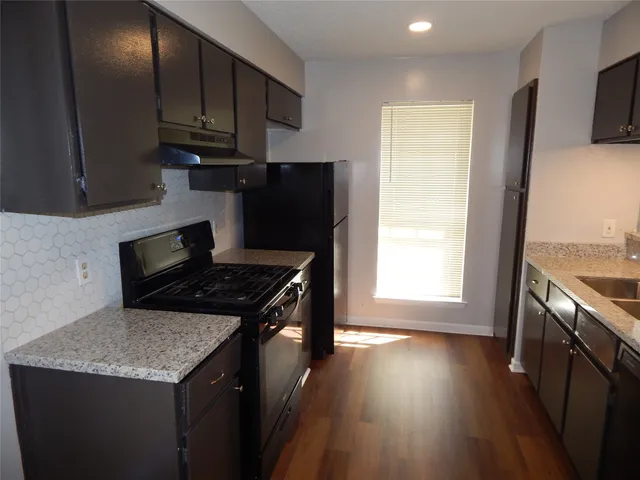 a kitchen with granite countertop a stove and a wooden floors