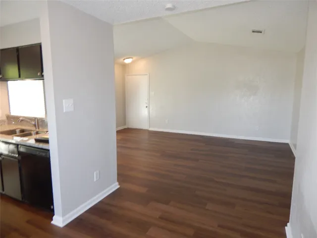 a view of kitchen and empty room with wooden floor