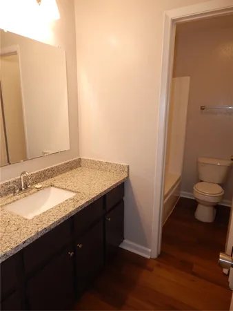 a bathroom with a granite countertop sink a toilet and a mirror