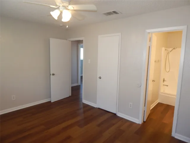 an empty room with wooden floor and a ceiling fan