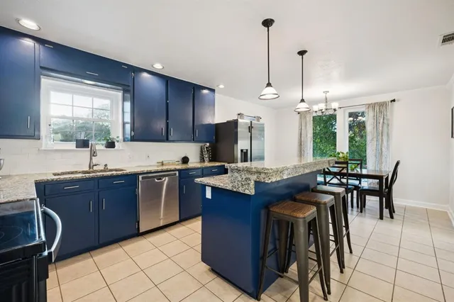 a kitchen with stainless steel appliances granite countertop wooden cabinets a stove a sink a dining table and chairs