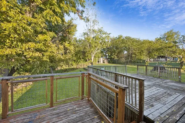 a balcony with wooden floor next to a yard