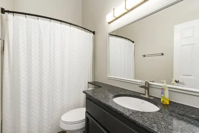 a bathroom with a granite countertop sink and a mirror with toilet