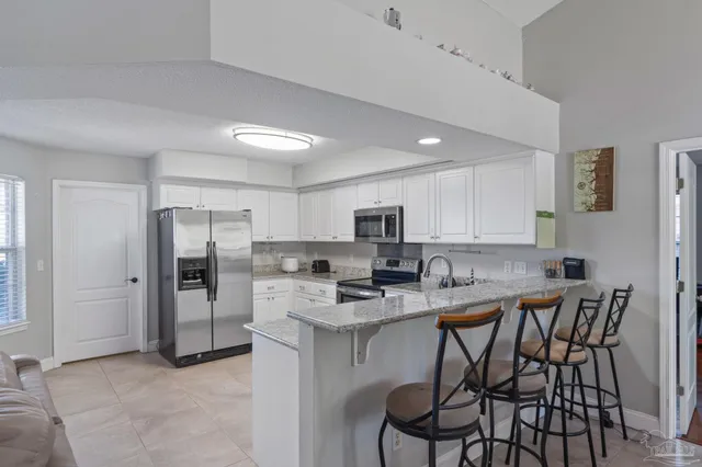 a kitchen with stainless steel appliances kitchen island granite countertop a table chairs refrigerator and a stove top oven