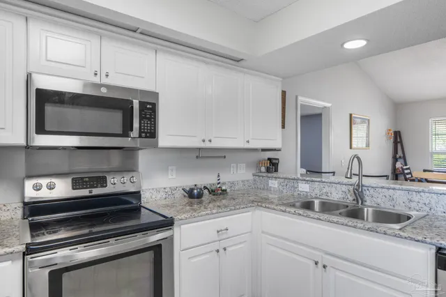 a kitchen with granite countertop white cabinets and appliances