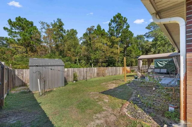 a view of a backyard with wooden fence and a small cabin