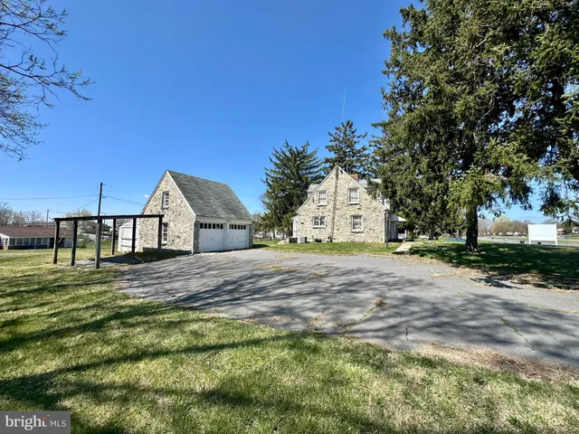 a view of a white house next to a yard with a large tree