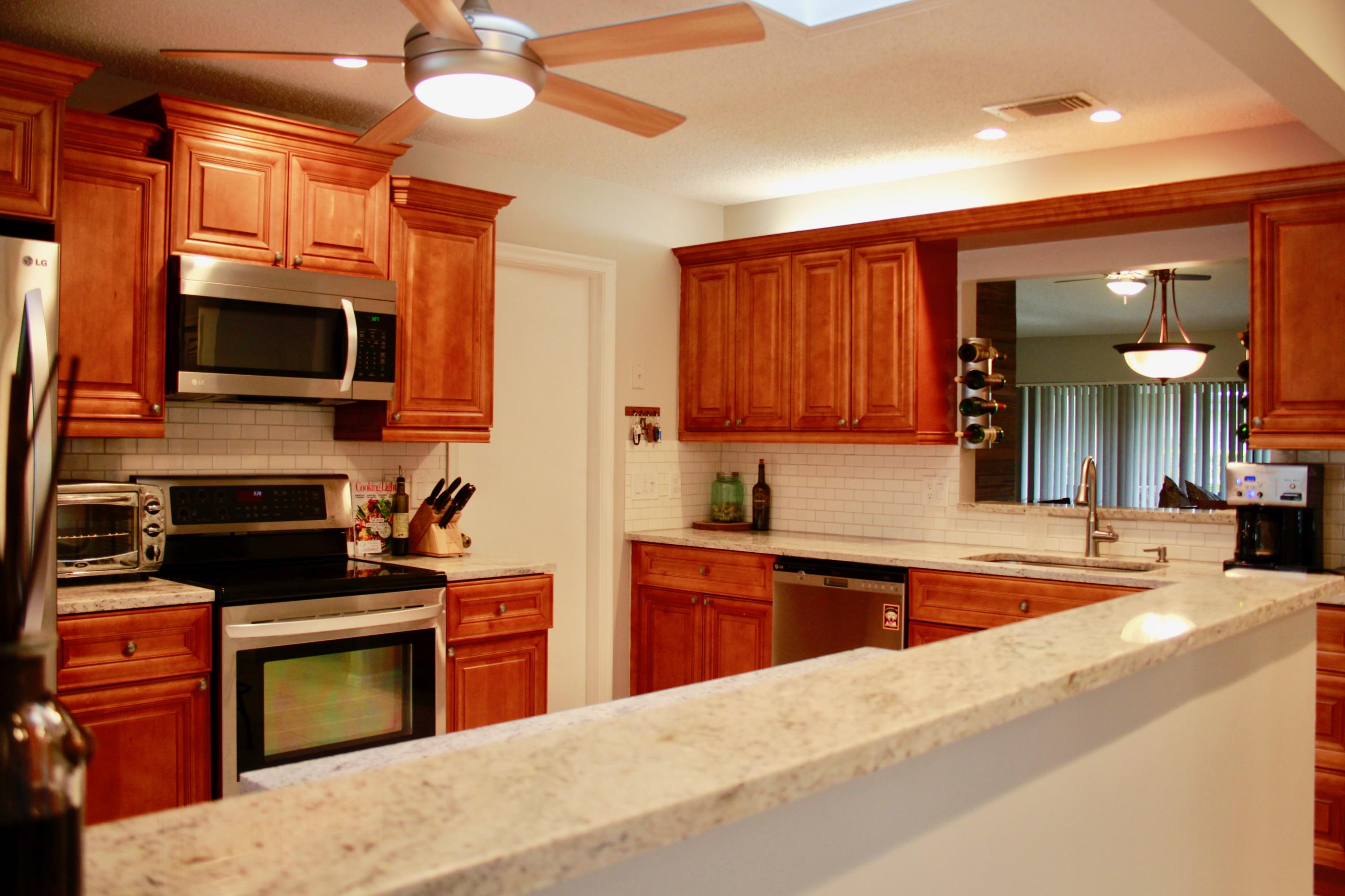 8986 Southwest 19th Street, Unit B Boca Raton, FL 33433 - Photo 3 of 55 a kitchen with stainless steel appliances kitchen island granite countertop a stove top oven a sink and dishwasher