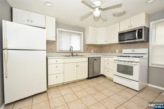 a kitchen with white cabinets and white appliances