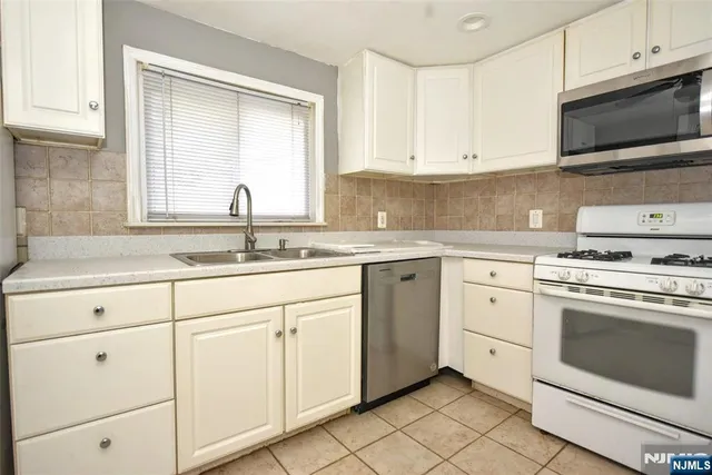 a kitchen with white cabinets appliances and a sink