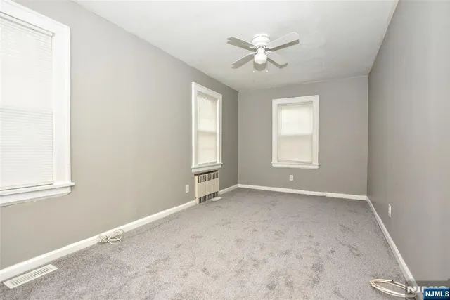 an empty room with windows and fan