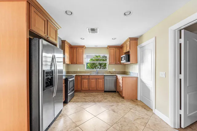 a kitchen with stainless steel appliances granite countertop a refrigerator and a stove top oven