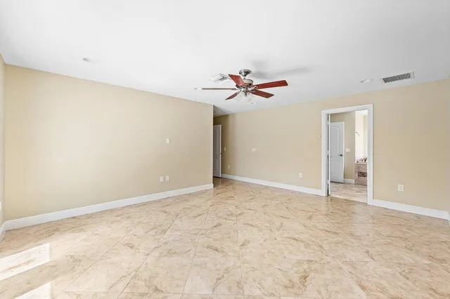 an empty room with windows and ceiling fan