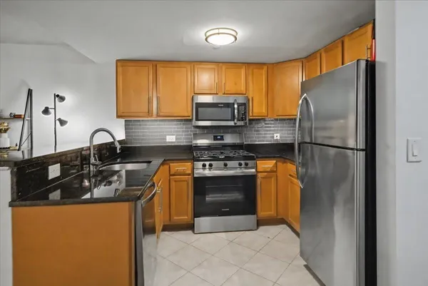 a kitchen with stainless steel appliances granite countertop a refrigerator sink and stove