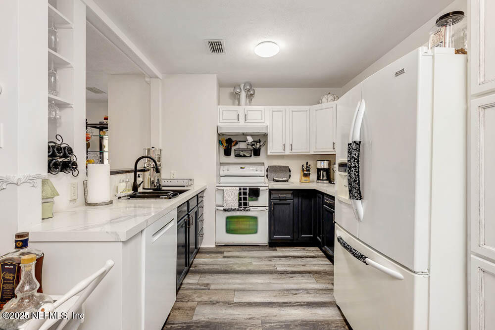 1228 Glen Laura Road Jacksonville, FL 32205 - Photo 5 of 40 a kitchen with stainless steel appliances granite countertop a refrigerator a stove and a sink with wooden floor