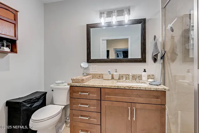a bathroom with a granite countertop toilet sink and mirror