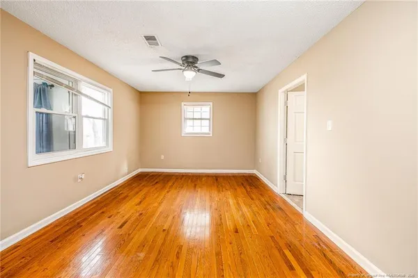 a view of a big room with wooden floor and windows