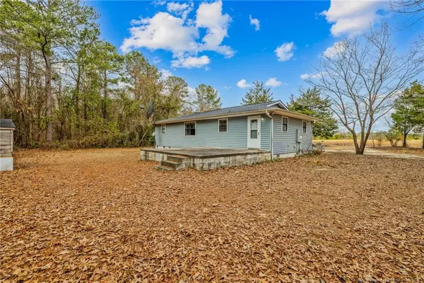 a view of house with outdoor space and trees in the background