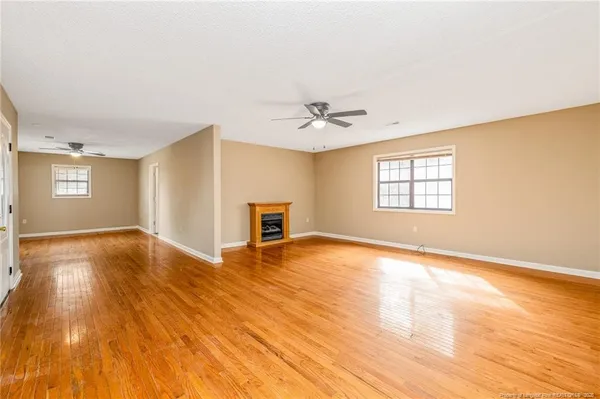 a view of an empty room with window and wooden floor