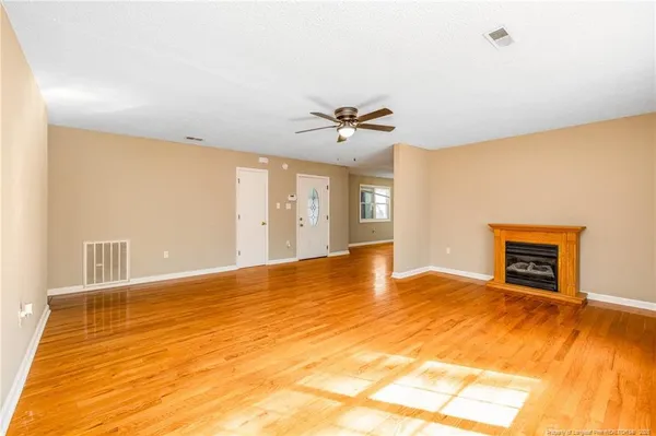 a view of an empty room with window and a kitchen