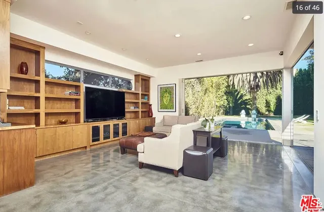 a living room with furniture a flat screen tv and floor to ceiling window