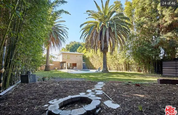 a front view of a house with a yard and palm trees