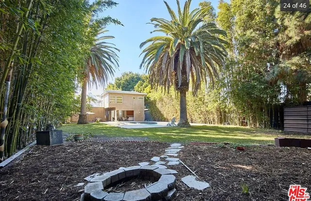 a front view of a house with a yard and palm trees