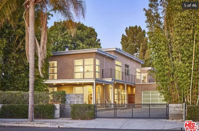 a front view of a house with glass windows and plants