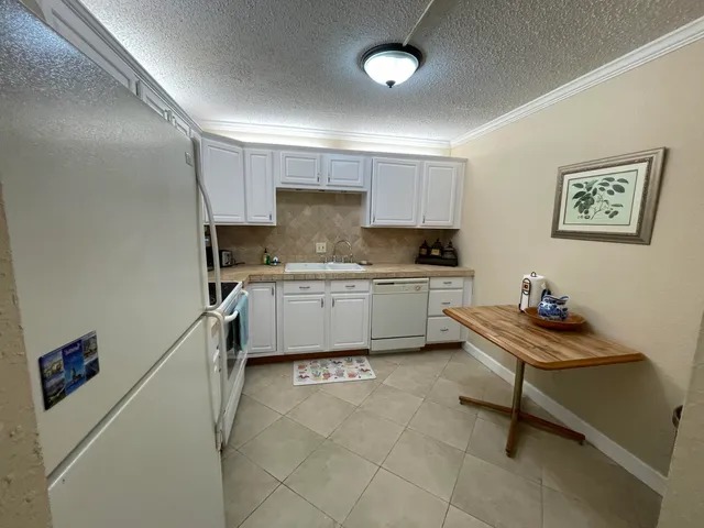 a kitchen with granite countertop white cabinets and white appliances
