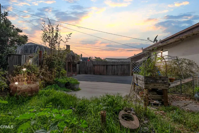 a view of backyard with potted plants and wooden fence