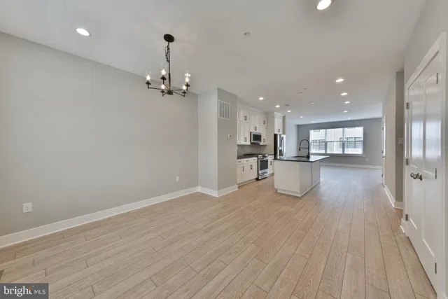 a view of an empty room with wooden floor and a ceiling fan