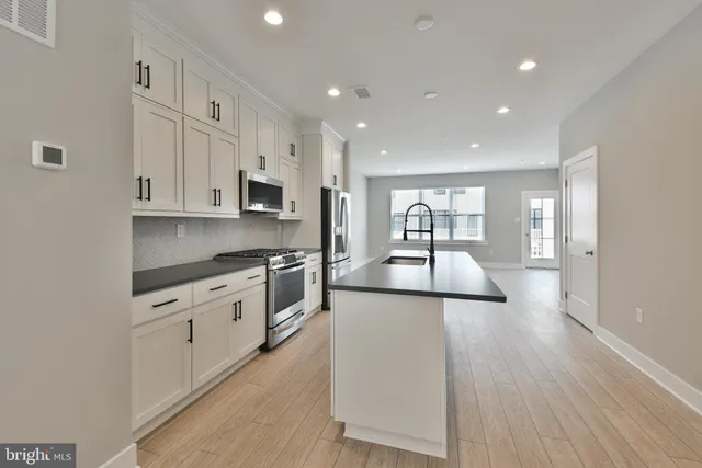 a kitchen with stainless steel appliances granite countertop a sink refrigerator and cabinets